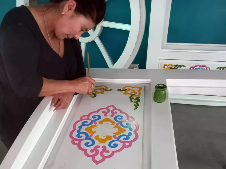 A women artist decorating a yurt window with traditional motif decoration