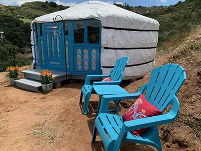 A yurt with windows, with chairs for guest outside, in Texas