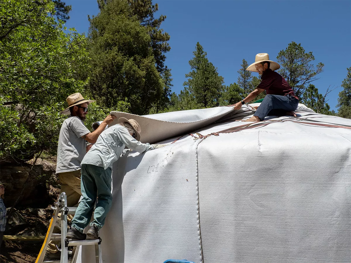 three people placing roof felt on a Mongolian yurt