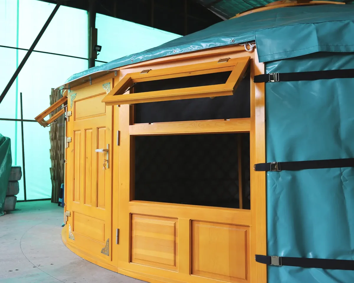 A Mongolian yurt in green cover, with wood windows and door painted in yellow