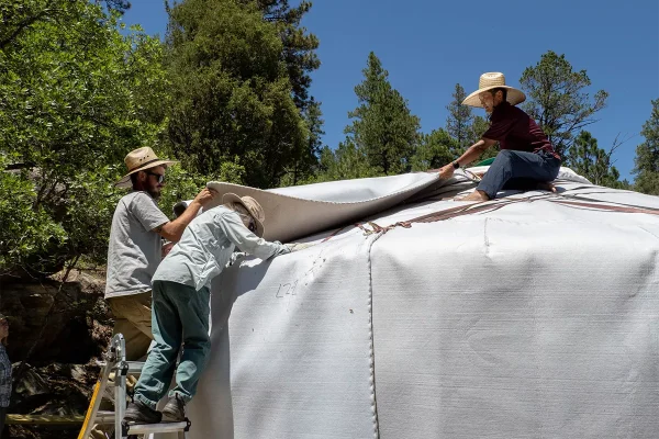 three people placing roof felt on a Mongolian yurt
